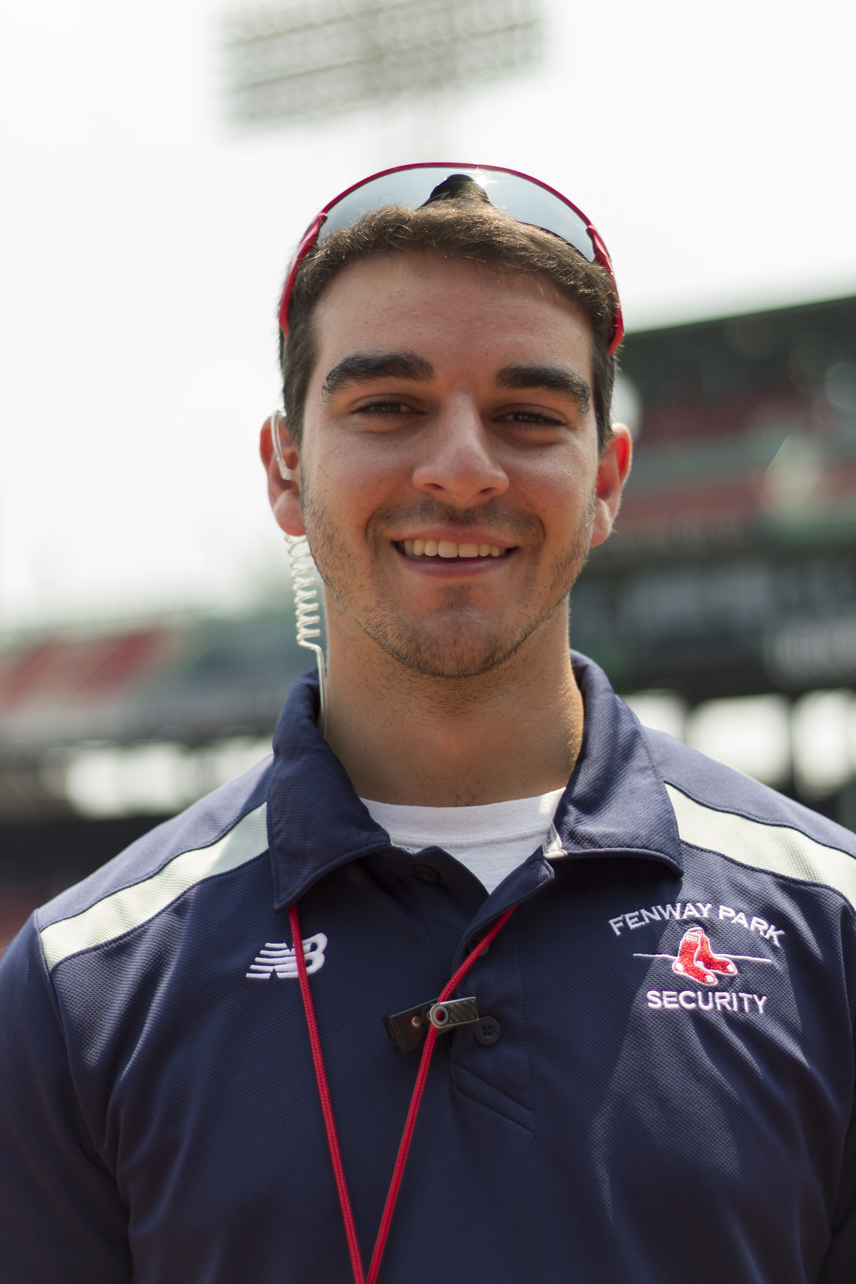 A white man wearing sunglasses and a Red Sox security uniform smiles at the camera.