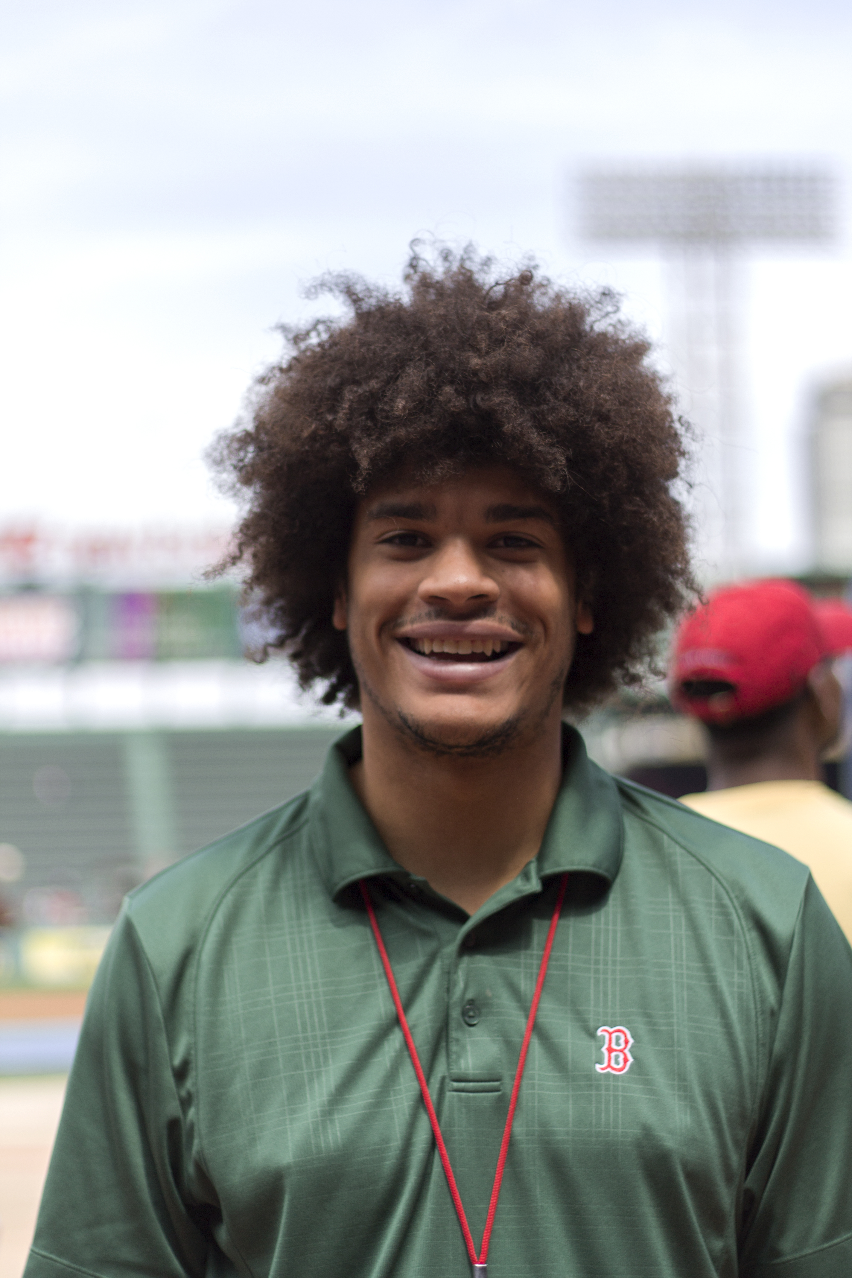 A Black man wearing a green Red Sox polo smiles at the camera.