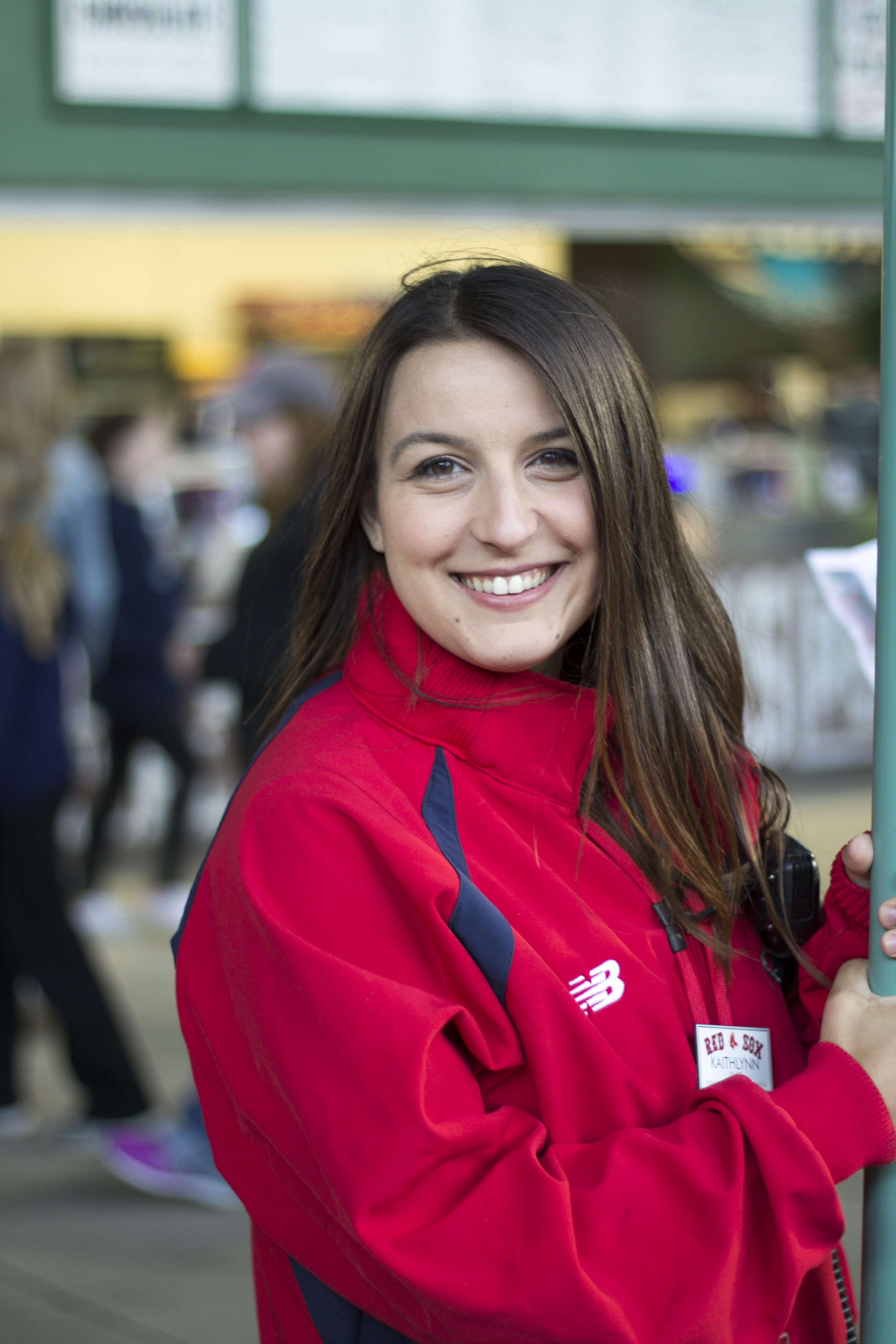 A white woman with long brown hair wearing and a Red Sox usher uniform smiles at the camera.